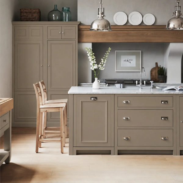 Chichester kitchen with cabinetry painted in Lead Light Beige, featuring a central island and oak bar stools.