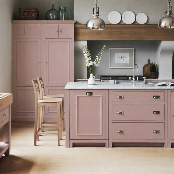 Chichester kitchen with cabinetry painted in Old Rose pink, featuring a central island and oak bar stools.