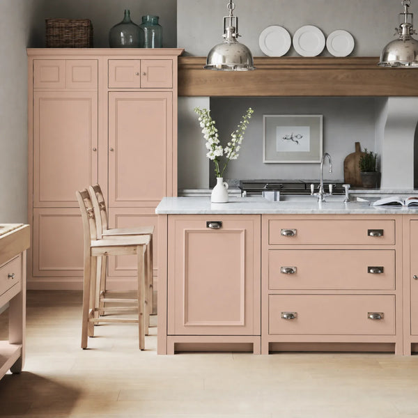 Chichester kitchen with cabinetry painted in Potters Pink, featuring a central island and oak bar stools.