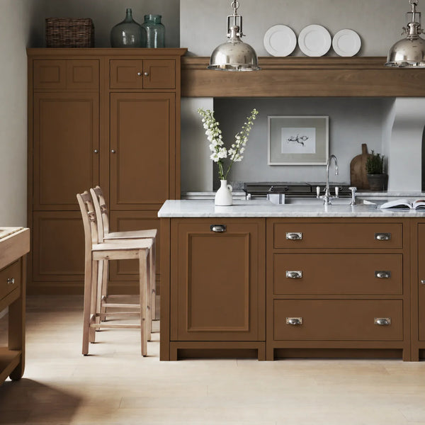 Chichester kitchen with cabinetry painted in Saddle brown, featuring a central island and oak bar stools.