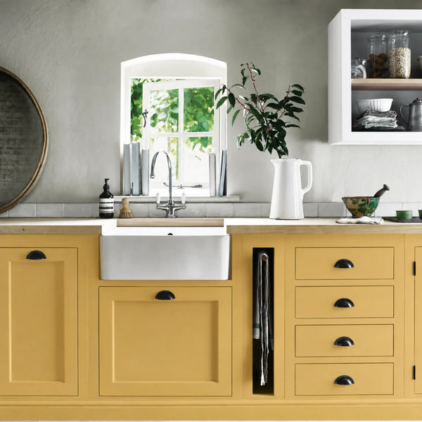 Saffron yellow painted Henley kitchen cabinetry with oak worktops and a white farmhouse sink.