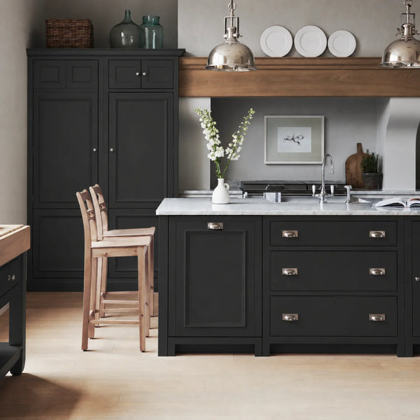 Chichester kitchen with cabinetry painted in Warm Black, featuring a central island and oak bar stools.