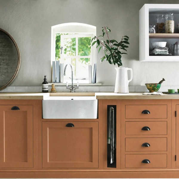 Burnt Sienna orange painted Henley kitchen cabinetry with oak worktops and a white farmhouse sink.