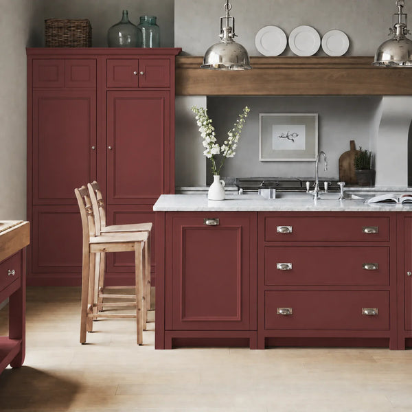 Chichester kitchen with cabinetry painted in Paprika red burgundy, featuring a central island and oak bar stools.
