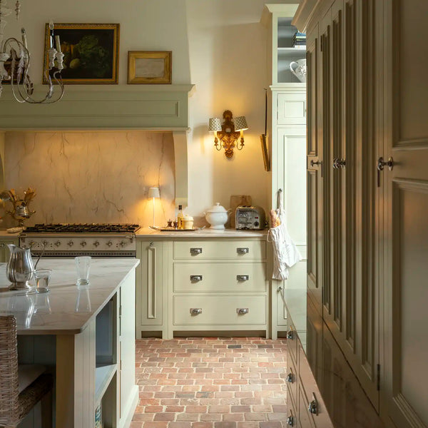 Traditional Chichester kitchen with dove grey painted cabinetry, marble worktops, brick flooring and a large range cooker.