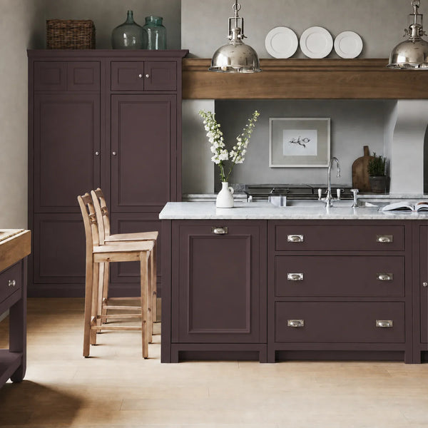 Chichester kitchen with cabinetry painted in Clove plum brown, featuring a central island and oak bar stools.