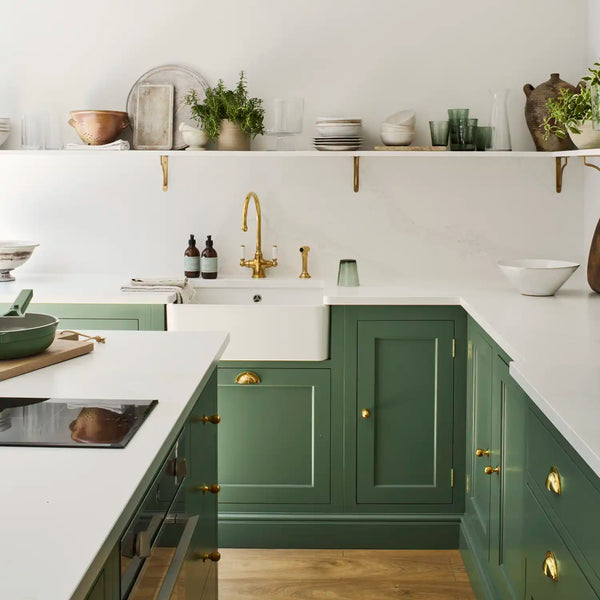 Henley kitchen painted in Cactus Green with farmhouse sink, brass hardware, open shelves and warm wooden flooring.