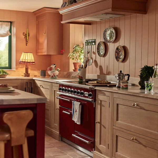 Traditional Henley oak kitchen with warm terracotta walls, red range cooker and brass hardware.