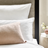 Albertine Pillowcases in Lily on a bed with soft neutral cushions