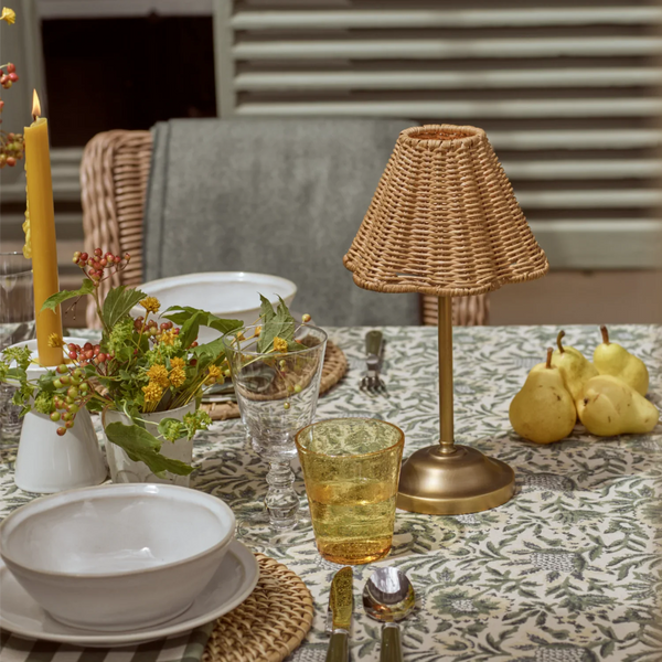 Athena Portable brass and rattan table lamp on garden dining table with seasonal place setting