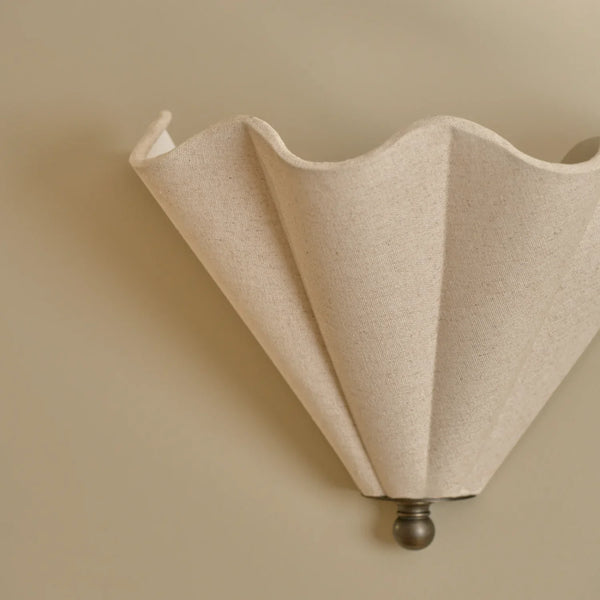 Athena linen scalloped wall light with bronze accents on beige wall