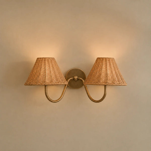 Athena brushed brass double wall light with rattan lampshades on cream wall, lights on