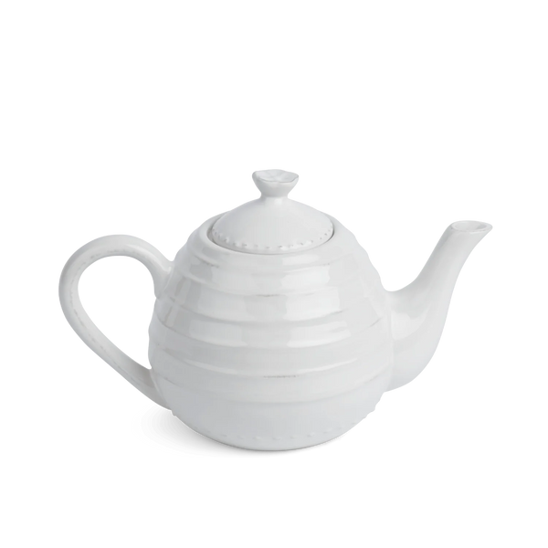 A white ceramic teapot with a ribbed, textured body, a curved handle, and a matching lid, shown on a plain white background.
