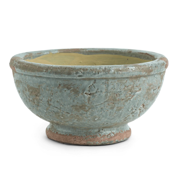 A handmade ceramic bowl with a textured, rustic finish, featuring a light blue-green glaze over a terracotta base, with a contrasting light yellow interior, shown on a plain white background.