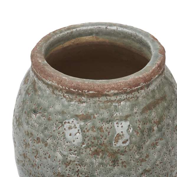 Close-up of a ceramic vase or planter with a rounded body, showing a textured glaze in muted sage green with brown speckling and a terracotta-colored rim, photographed on a white background.