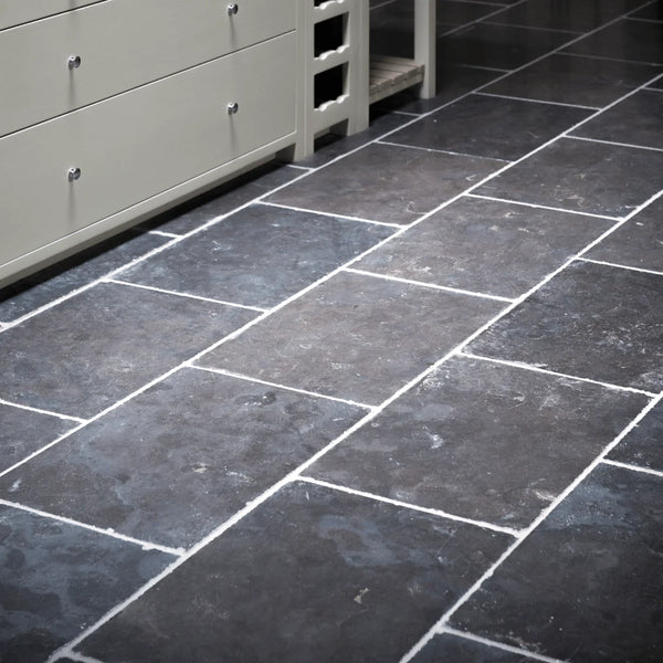 Dark charcoal gray rectangular stone tiles with white grout lines, shown in a room setting with a light gray cabinet on the left.