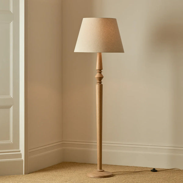 Chalford natural oak floor lamp with linen shade in a carpeted room with beige walls, lights on