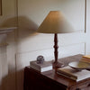 Chalford Darkened Oak Table Lamp with Linen tapered lamp shade on side table with coffee table books and ornaments