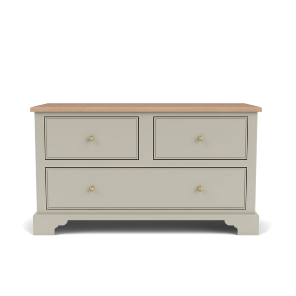 A classic four-drawer chest of drawers in a warm grayish-beige finish with a natural light wood top and small brass knobs, shown on a clean white background.