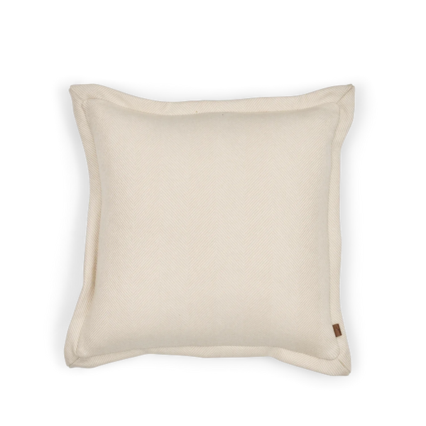 A square off-white woven throw pillow with a subtle diagonal texture and a small brown fabric tag on the bottom right corner, shown against a plain white background.
