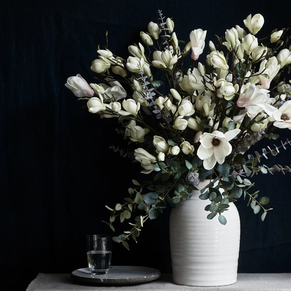 Faux flower bouquet, featuring Eucalyptus spray and magnolia, in large ceramic vase