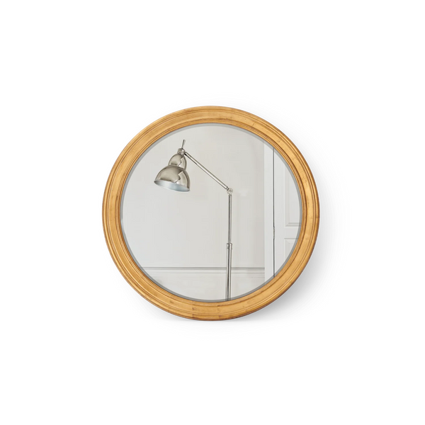 Round wall mirror with a natural bamboo wood frame, reflecting a silver adjustable floor lamp against a white paneled wall.