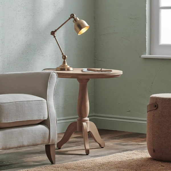 Wooden side table with a lamp next to a gray armchair in a room with green walls.