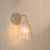 Lennox wall light with brushed nickel base and glass shade on wall, light on