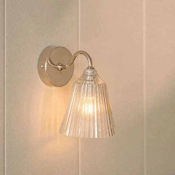 Lennox wall light with brushed nickel base and glass shade on wall, light on