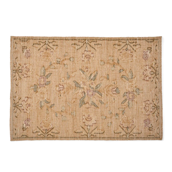 A rectangular woven area rug with a natural jute or straw base, featuring a faded floral and botanical pattern in muted pink, sage green, and brown tones, shown flat against a solid white background.