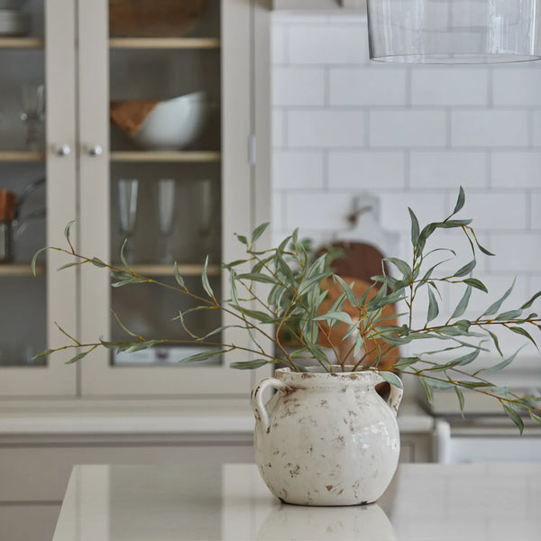Faux olive spray displayed in an urn ceramic vase in modern country kitchen