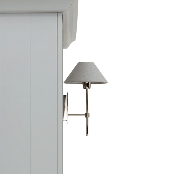 A modern wall-mounted sconce with a gray fabric drum shade and polished silver metal arm, shown mounted on a white cabinet against a white background.