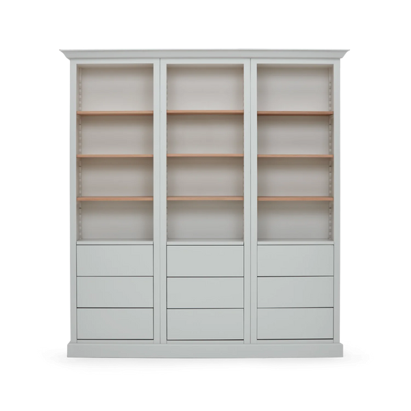 A tall, light gray bookcase with three columns of shelving and drawers, shown against a plain white background.