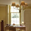 Regency small four light pendant in brass with linen shades, in elegant office with wooden desk overlooking country garden