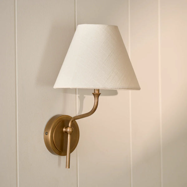 Regency wall light in brass with linen shade on cream wall