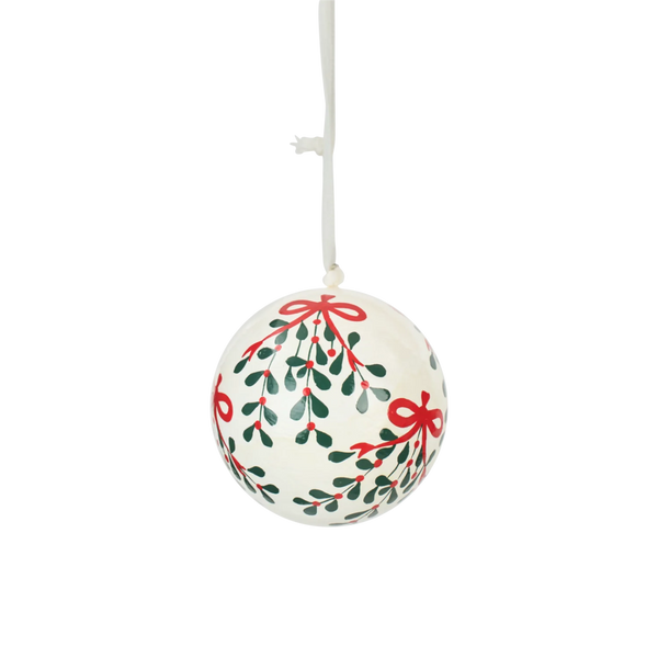 A round hanging Christmas ornament with a white background and a hand-painted mistletoe pattern featuring green leaves, red berries, and red bows, suspended by a white string.