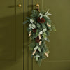 A hanging green garland with pinecones, eucalyptus leaves, and small white berry clusters, displayed against an olive green paneled door.