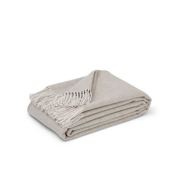 A folded light beige woven throw blanket with cream fringe, displayed on a clean white background.