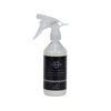 A clear plastic spray bottle filled with white liquid, featuring a black label with the brand name 'IsoGuard' and the text 'Tanning Spot Remover'. The spray trigger is white and transparent, set against a plain white background.
