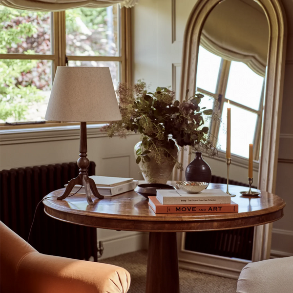 Thornbury darkened oak table lamp on wooden side table, with decorative vases and candles, beside a floor length mirror in living room