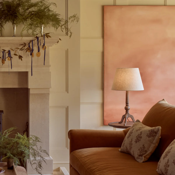 Thornbury darkened oak table lamp on wooden side table, beside a sofa and fireplace in living room