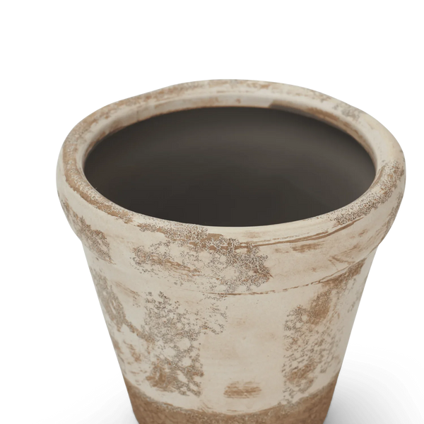 A close-up of a terracotta-style planter pot with a distressed, rustic finish. The pot features a warm beige and brown textured exterior with a smooth, dark gray interior, shown against a plain white background.