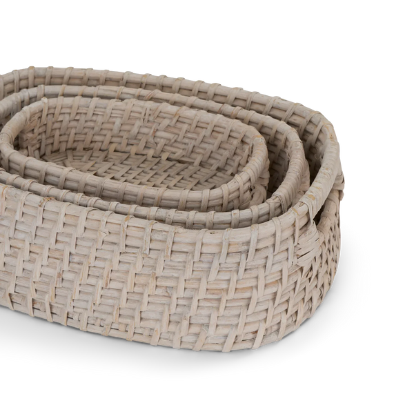 Three nested oval woven baskets made from natural light beige reed or straw, shown on a clean white background.