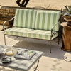 Outdoor patio set with green and white striped cushions on a metal frame.