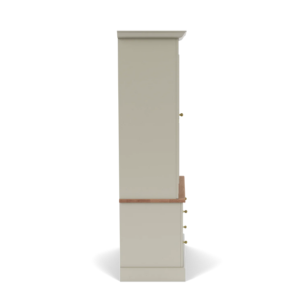A tall, narrow cabinet or hutch shown from the side on a clean white background. The main body is a warm light beige or greige, with a medium brown wood apron and drawer front, and small brass/gold knobs.
