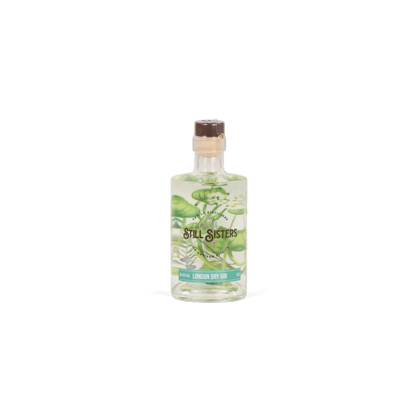 A small clear glass bottle of Still Sisters Lemon Dry Gin with a cork stopper, featuring a green botanical label, set against a plain white background.