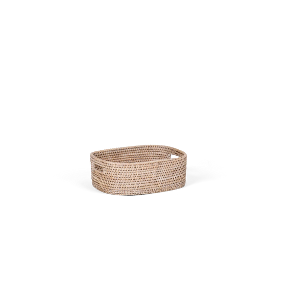 A small oval rattan storage basket with cutout handles, made from natural tan reed or wicker, shown on a plain white background.