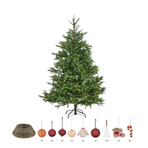 A pre-lit artificial Christmas tree with green needles and warm white lights, shown on a black metal stand against a white background. Below the tree, a row of included accessories is displayed with quantity labels: a wicker tree skirt (x6), three red ornaments (x6), one orange striped ornament (x6), one cream ornament (x6), a floral ornament (x6), a white bell ornament (x12), a red and gold sleigh ornament (x6), and a candy cane ornament (x6).